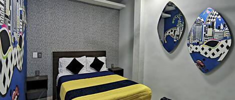 Un dormitorio con una cama, un ventilador de techo, una pared con un mural de paisaje urbano y un cubo de basura.