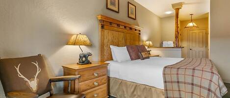 A hotel room with a bed, a chair, a nightstand, a lamp, and a mirror.