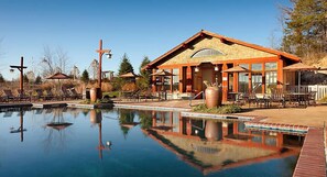 A poolside area with a building, lounge chairs, and a cross.