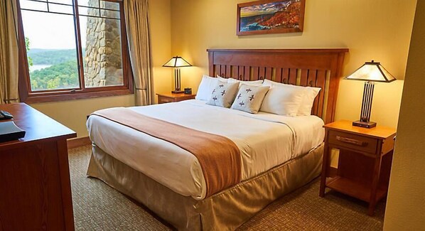 A hotel room with a large bed, two bedside lamps, a desk, and a window offering a scenic view. - Luxurious units at The Cliffs at Long Creek! (Ridgedale)
