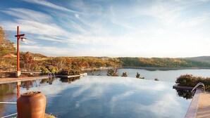 Una piscina infinita con vistas a un lago y follaje otoñal.