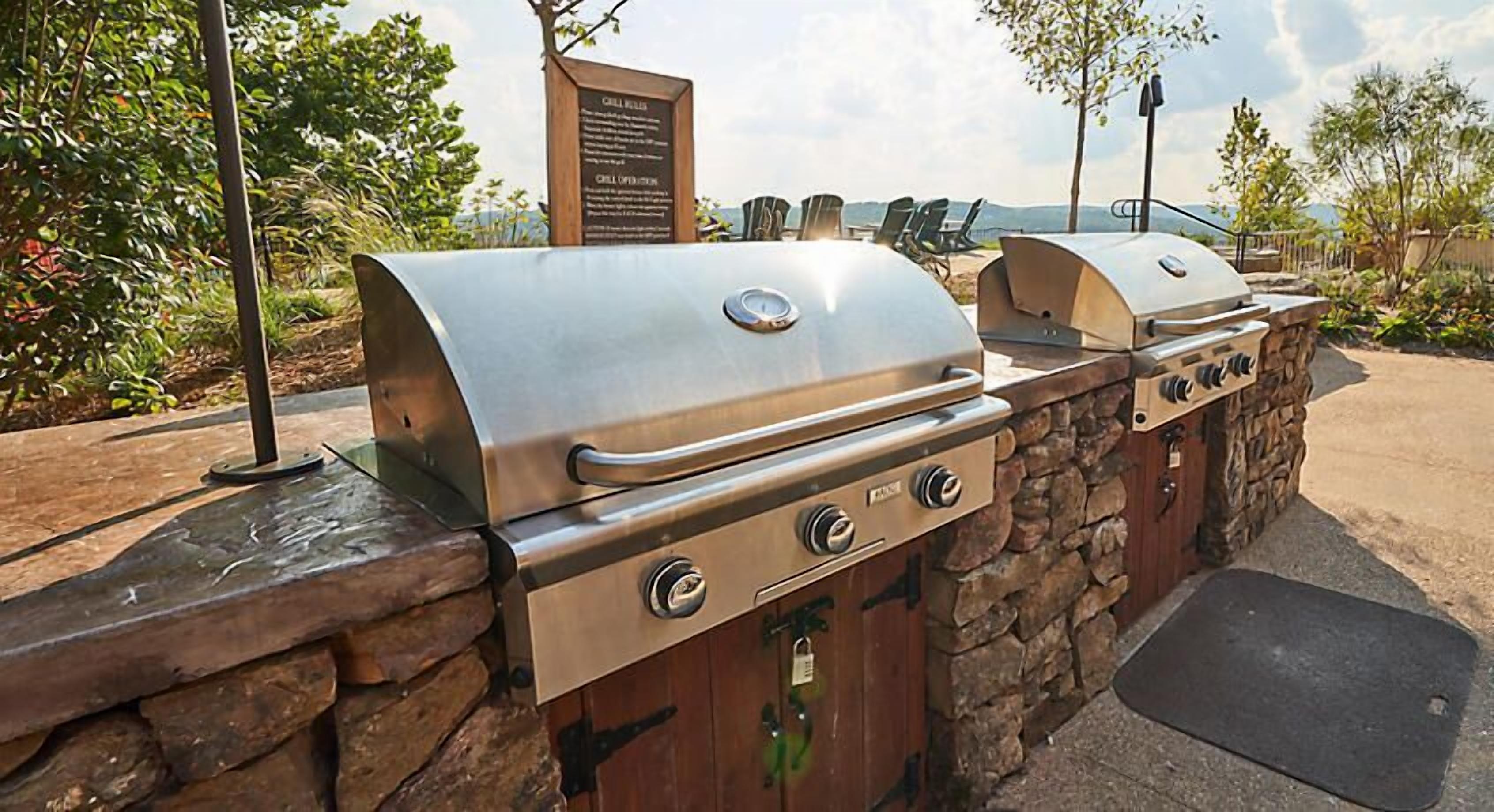 A barbecue area with two grills, a stone wall, and a signboard.