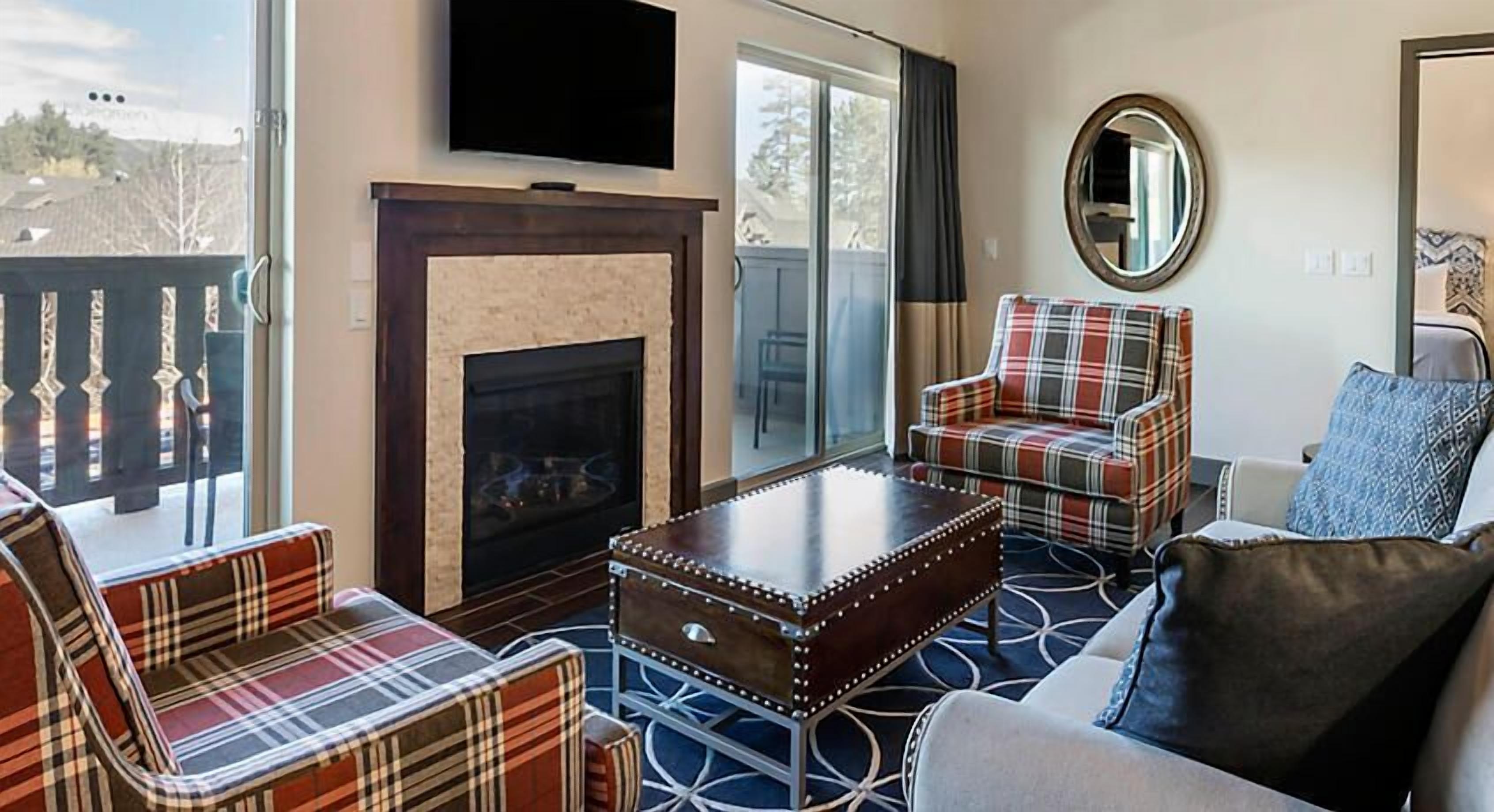 A living room with a fireplace, plaid furniture, a television, and a large window.