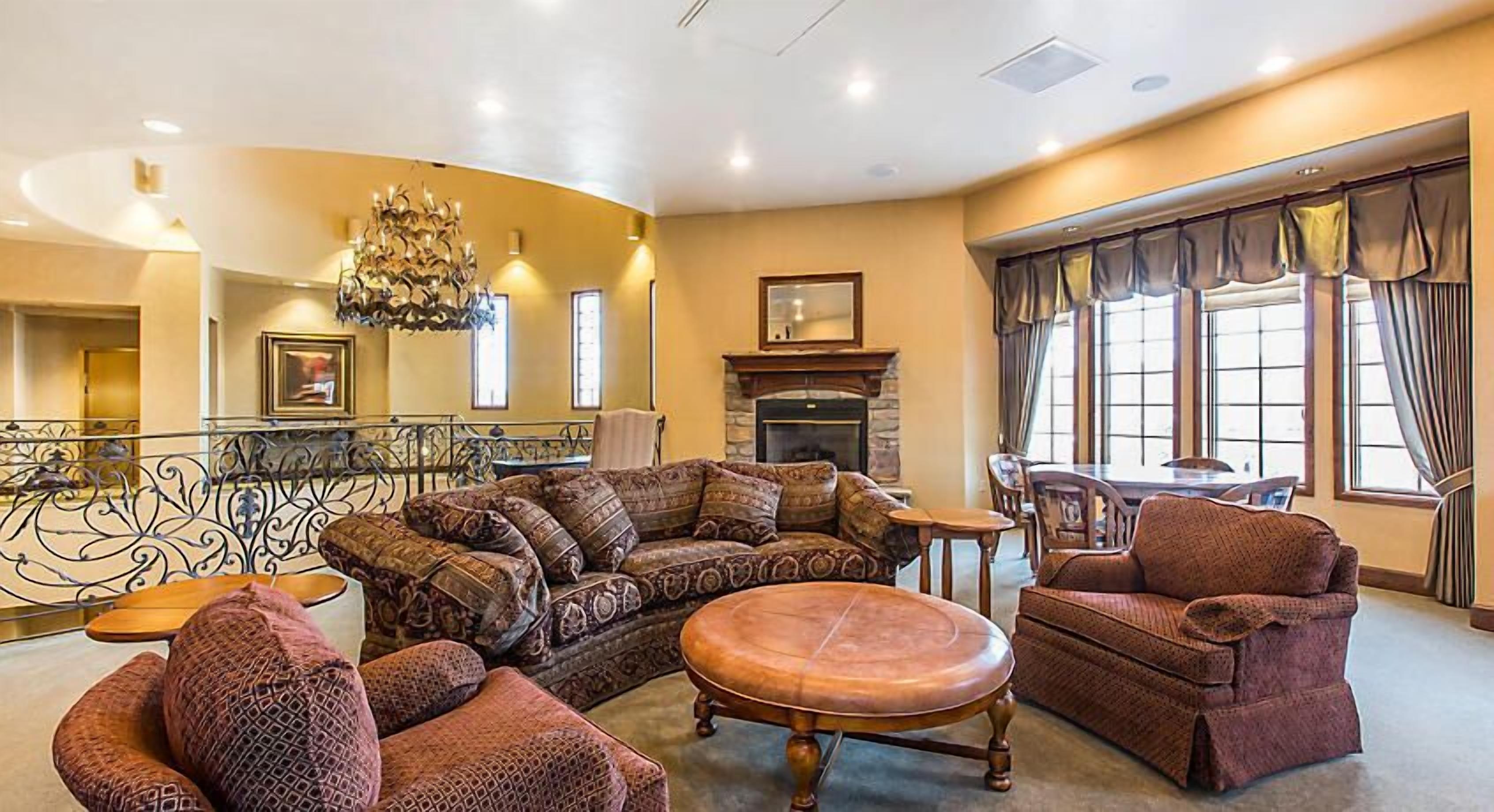 A spacious living room with a fireplace, comfortable seating, and large windows.