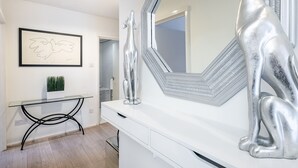A modern bathroom with a large mirror, a framed artwork, and a glass table with a plant. - Elegant Two bedroom in the heart of Kensington (London)