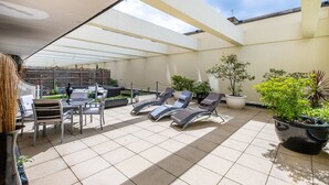 A sunlit patio with tiled flooring, outdoor seating, and potted plants. - Elegant Two bedroom in the heart of Kensington (London)
