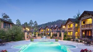 A resort with a central pool, multiple guest rooms, and a mountainous backdrop.