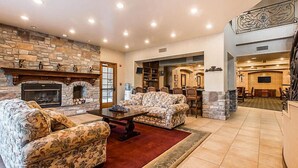 A spacious living room with a stone fireplace, floral-patterned sofas, and a dining area with wooden chairs.