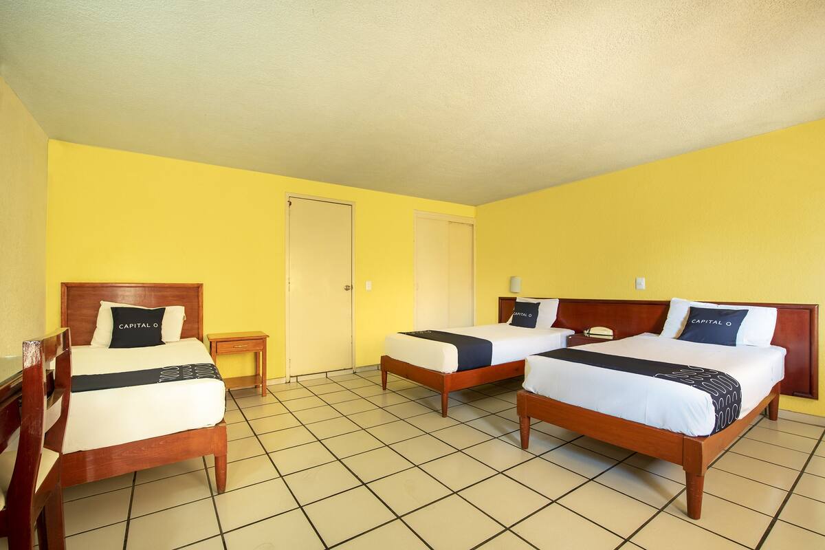 A hotel room with two beds, a wooden headboard, a small bedside table, and a door.