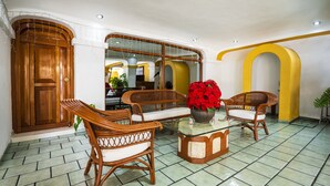 A lobby with wicker furniture, a glass-top coffee table, and a large mirror. - Capital O Colón,  Ciudad Guzmán Jalisco (Zapotlán el Grande)