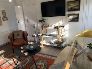 Relax in this inviting living space with a comfortable armchair, flat-screen TV, and decorative artwork.