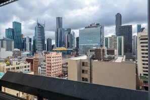 A city skyline with modern high-rise buildings, a mix of architectural styles, and a cloudy sky.