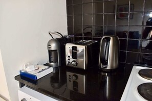 A kitchen with a coffee maker, toaster, and kettle on a black countertop. - Spacious CBD Apt in the Heart of Melbourne (Melbourne)