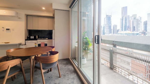 A modern kitchen with a dining area, large sliding glass doors, and a city view.