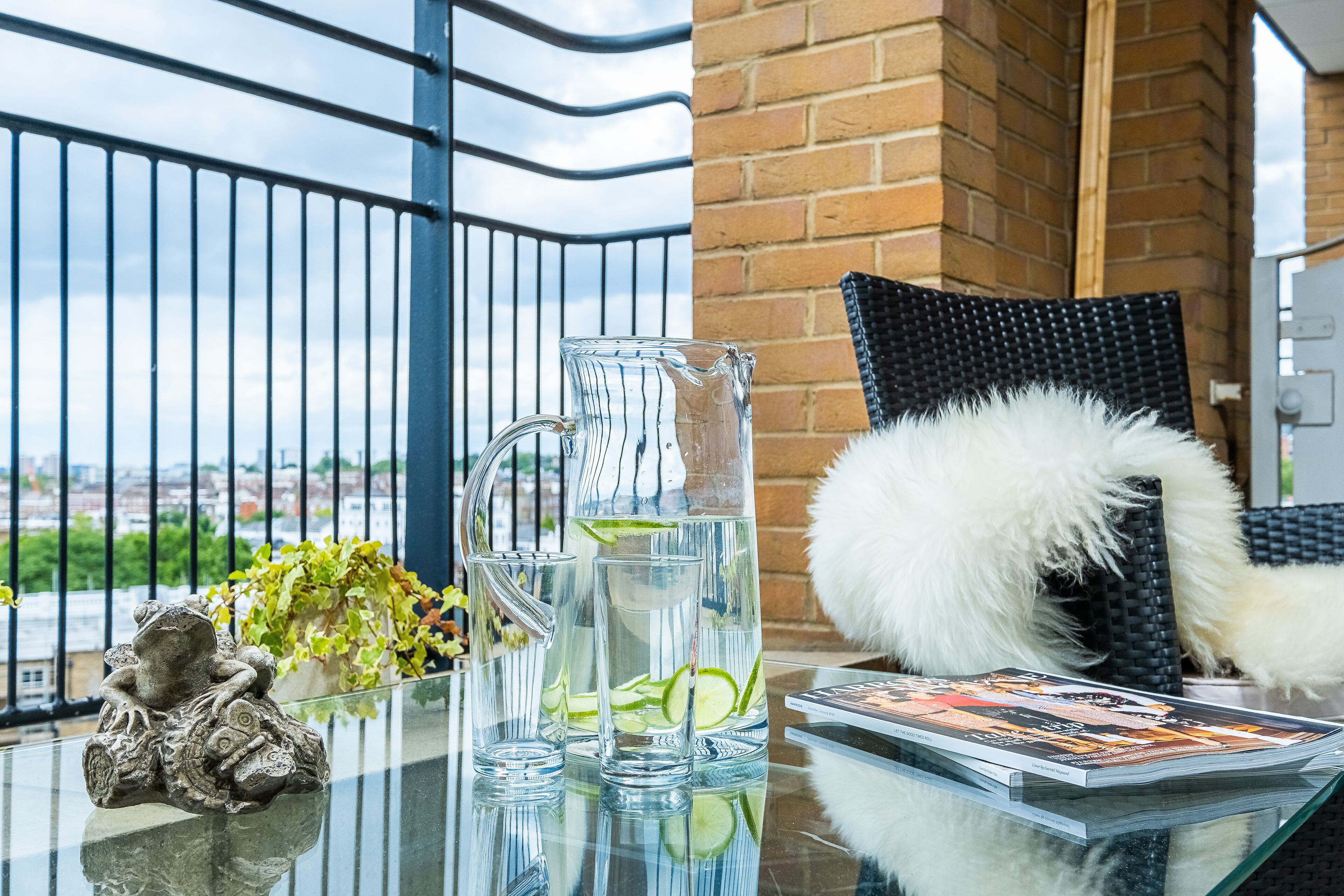 A glass table with a pitcher, a magazine, and a small statue.