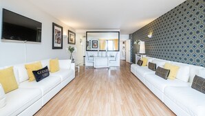 A modern living room with two white sofas, a coffee table, and a TV mounted on the wall.