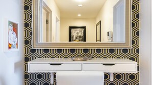 A bathroom with a white vanity, a large mirror, and a geometric patterned wall.