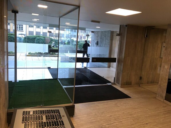 A modern office space with glass walls, a wooden floor, and a black mat in the center.