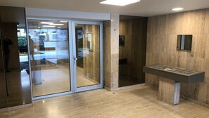 Interior moderno com entrada por porta de vidro, piso de madeira e mesa de pebolim embutida.