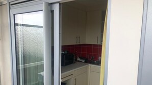 Uma cozinha compacta com micro-ondas, armários e painel de azulejos.