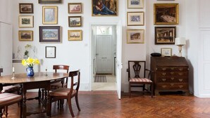 Un coin repas avec une table et des chaises en bois, entouré de tableaux encadrés accrochés aux murs.