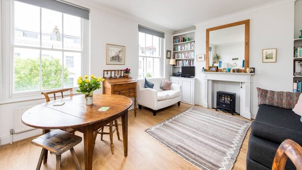 A living room with a fireplace, a dining table with chairs, a sofa, and a bookshelf.