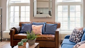 Un salon avec un canapé en cuir marron, un canapé bleu et une table basse en bois sur laquelle est posée une plante en pot.