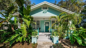A house with a green roof and white trim, surrounded by lush tropical plants. - Quaint Bungalow just off Main Street! (Dunedin)