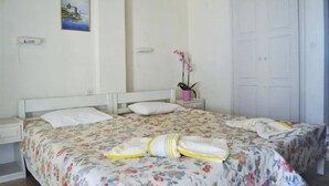 A bedroom with a bed, a nightstand, a potted plant, and a door. - Ionian View Studios (Corfu)