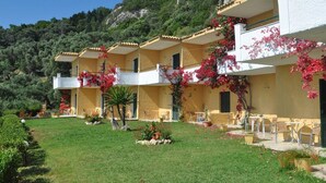 A hotel with multiple balconies, outdoor seating, and a lush garden. - Ionian View Studios (Corfu)