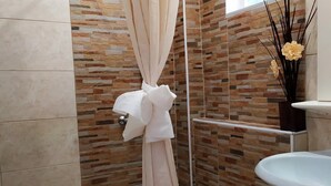 A bathroom with a shower curtain, a sink, and a decorative vase with flowers. - Ionian View Studios (Corfu)