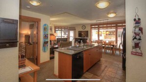 Una cocina con una isla central, armarios de madera y un comedor con mesa y sillas.