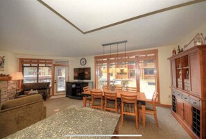 A living room with a sofa, a dining table with chairs, a TV, and a cabinet. - 3B/3BA The Village At Mammoth, Corner Suite In The Clock Tower, Amazing Location (Mammoth Lakes)