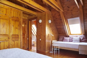 A wooden cabin bedroom with a loft bed, a small table, and a window with a view.