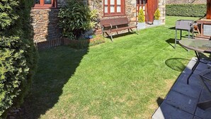 A stone building with a sloped roof, wooden balconies, and a well-maintained lawn. - El Jardi Secret by FeelFree Rentals (Escuñau)