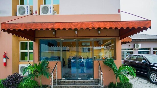 A building with a glass entrance, steps leading up to it, and two air conditioning units on the roof. - Bleu Ivy Hotel & Suites (Lagos)