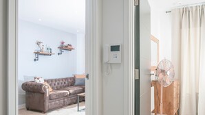 Ein modernes Wohnzimmer mit einem braunen Ledersofa, einem weißen, flauschigen Teppich und einem Holzschrank mit einem Ventilator.