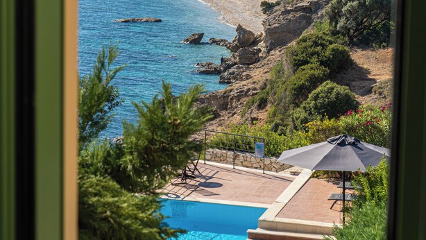 A view of a beach resort with a swimming pool, lounge chairs, and a clear blue sea. - Three-Bedroom Seafront Villa, Brio Complex | Private Pool & Jetty | Sleeps 6–8 (Kefalonia Island)