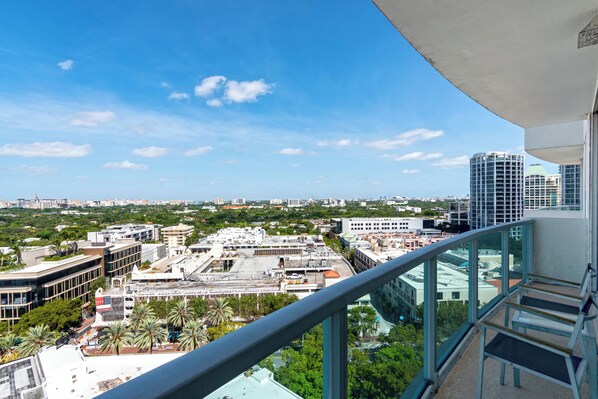 A high-rise building with a view of a cityscape, including various buildings and palm trees.