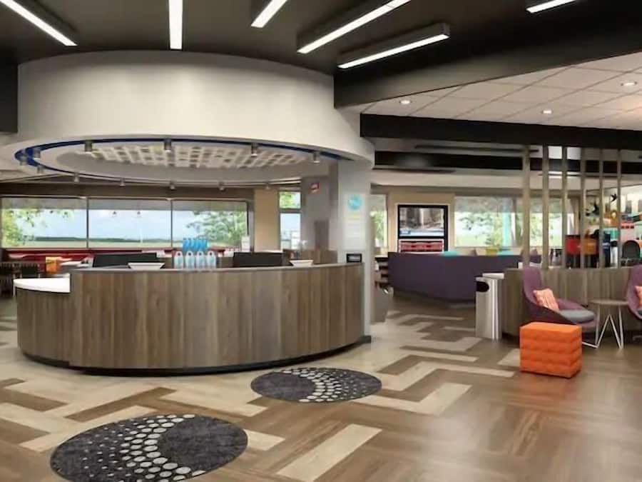 A modern lobby with a central reception desk, seating areas, and a patterned floor.