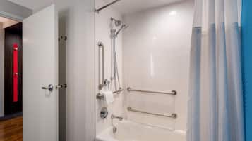 A modern bathroom with a walk-in shower, grab bars, and a white bathtub.
