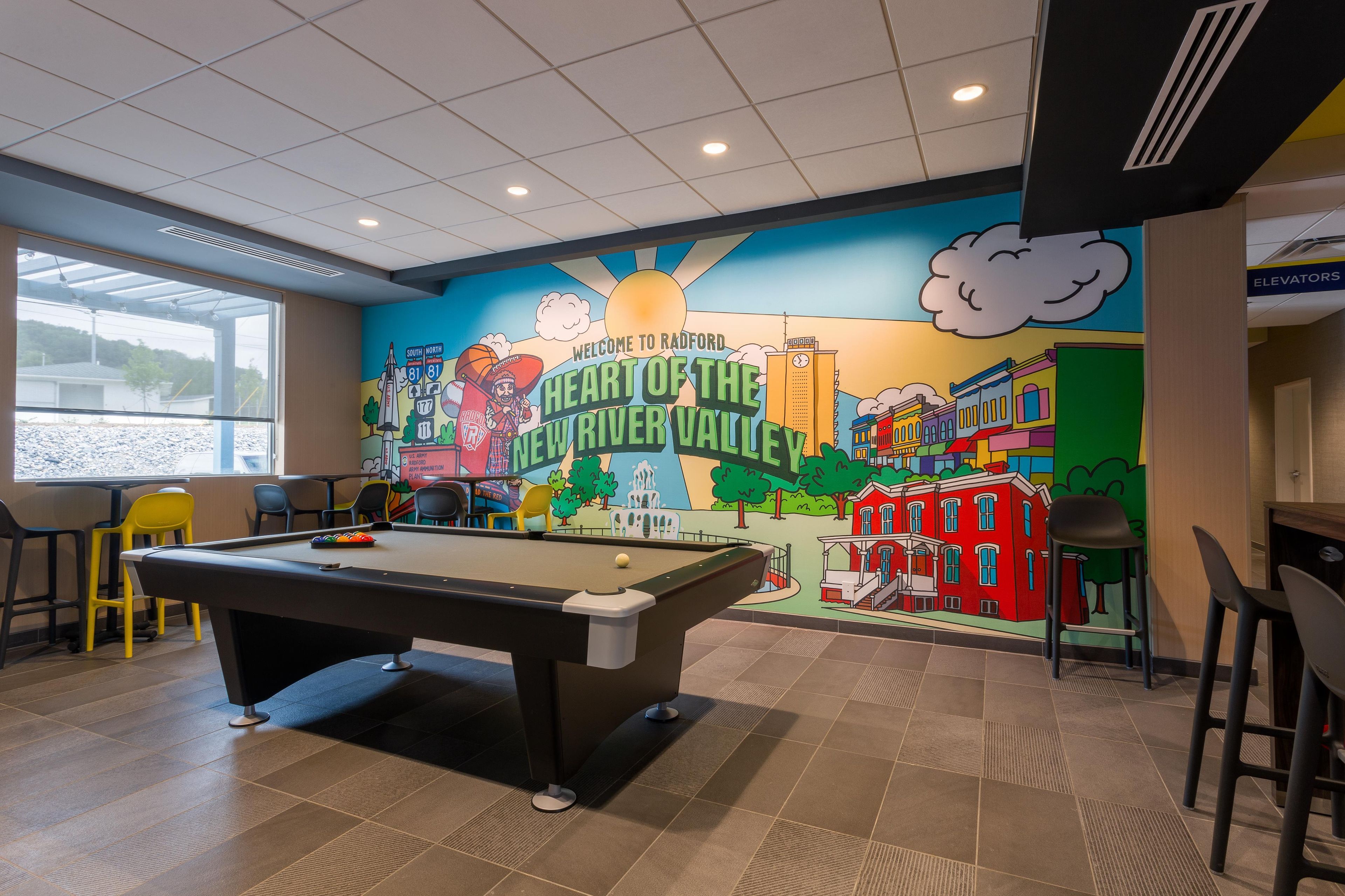Een pooltafel in een ruimte met een muurschildering van een stadsbeeld, inclusief een klokkentoren en gebouwen.