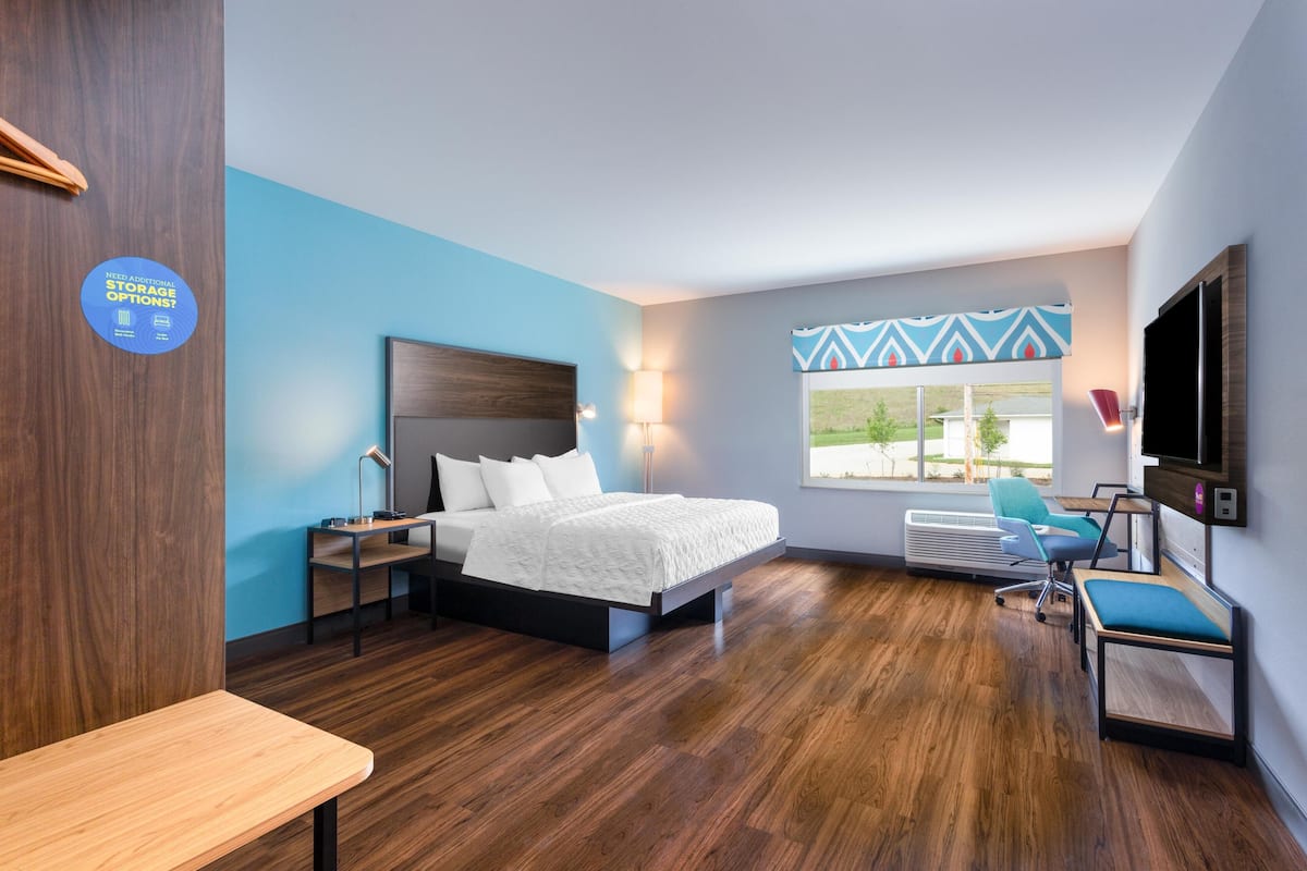 Una habitación de hotel moderna con cama, escritorio, silla y televisión.