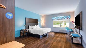 Een moderne hotelkamer met een bed, bureau, stoel en een televisietoestel.