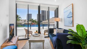 A modern living room with a sofa, a coffee table, and a TV on a wooden stand. - Surfers Paradise 2-Bed Near Beach with Pool & Gym (Surfers Paradise)