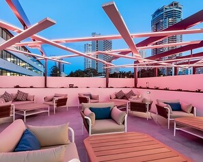 Un salón en la azotea con asientos al aire libre y vistas a edificios de la ciudad.