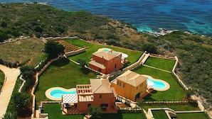 An aerial view of a coastal property with a swimming pool, a tennis court, and a large house with a Mediterranean architectural style. - Villa A, Brio Exclusive | 3BR Seafront Family Villa with Private Pool & Jetty (Kefalonia Islands)