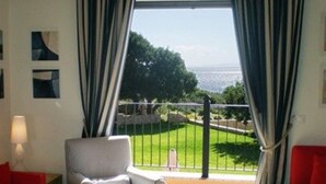 Une pièce avec vue sur la mer, un canapé rouge, un fauteuil blanc et une petite table.