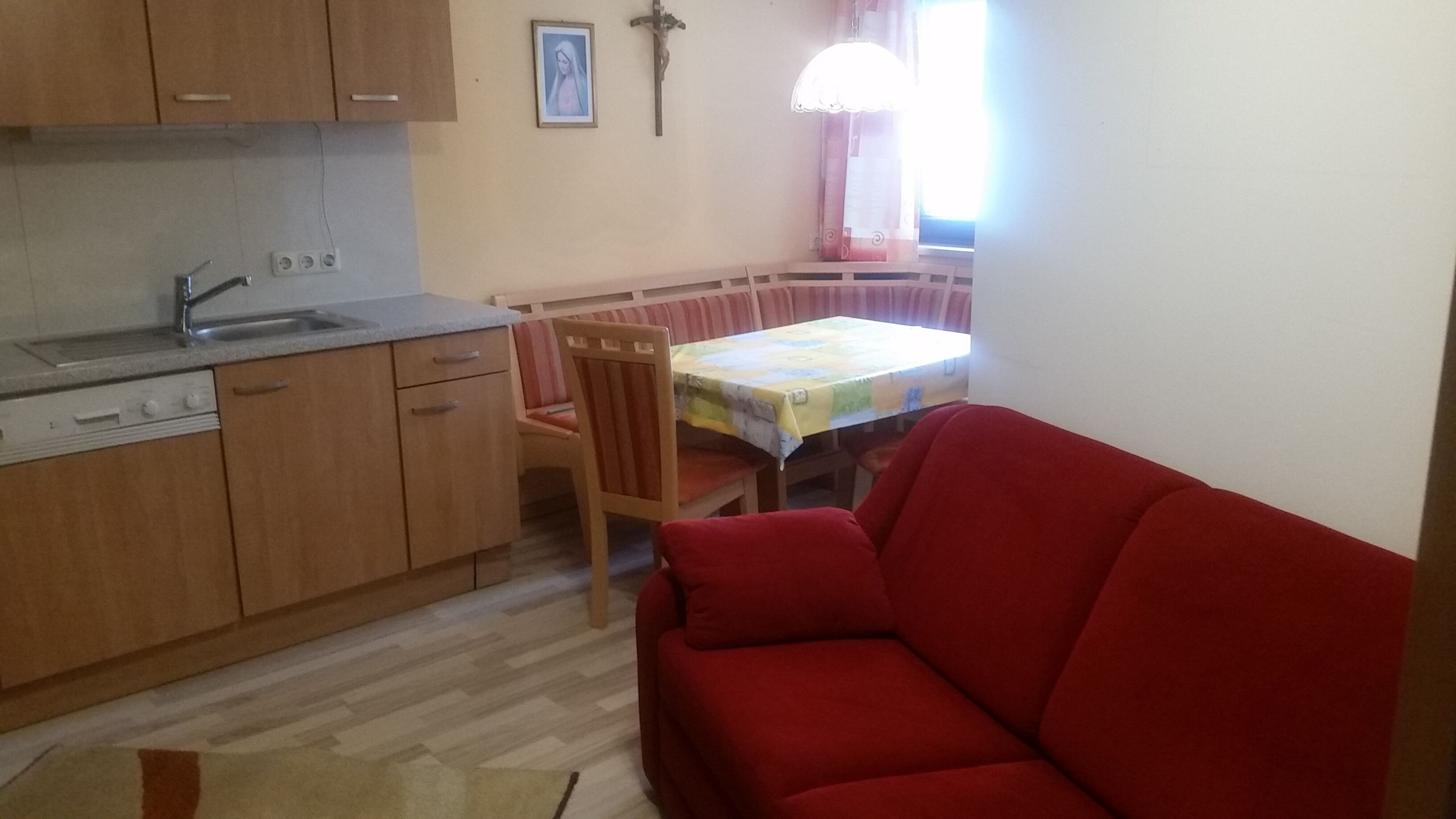 Une cuisine compacte dotée de meubles en bois, d’un évier et d’un coin repas avec une table et des chaises.