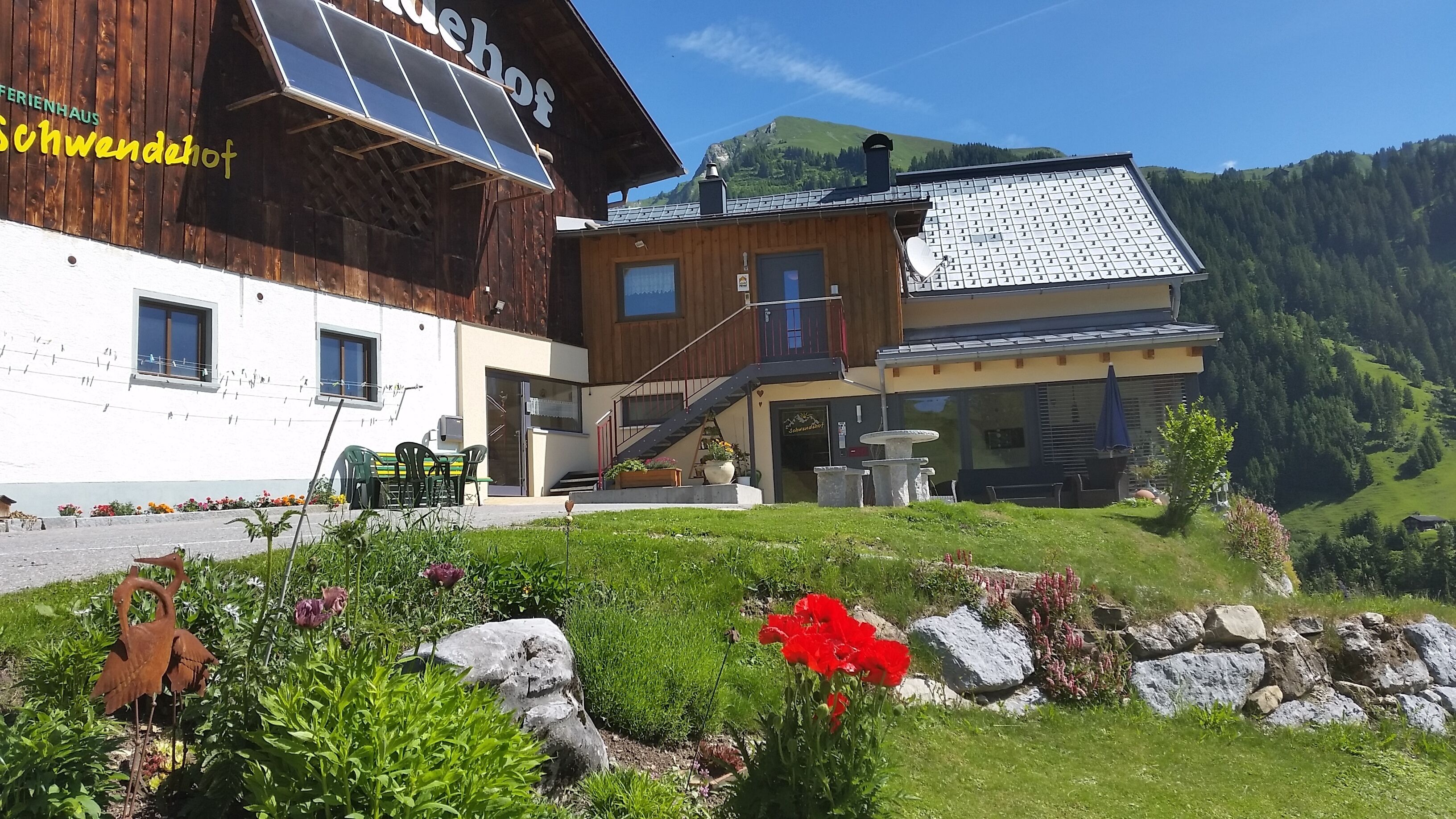 A two-story building with a wooden facade, solar panels, and a balcony.